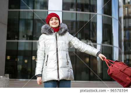 young happy woman in a warm jacket with a backpack travels the cities 96578394