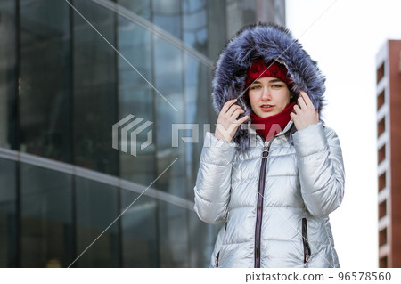 woman in a warm jacket on the street near the building 96578560