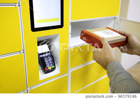Close up of a man picks up mail from automated self-service post terminal machine Close up of a man picks up mail from automated self-service post terminal machine 96579196