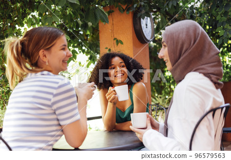 Multiethnic group of girls wearing casual clothes and traditional hijab having fun outdoors 96579563