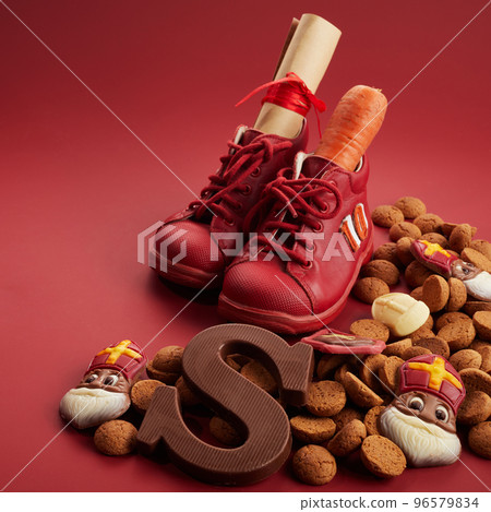 Saint Nicholas - Sinterklaas day with shoe, carrot and traditional sweets on red background Saint Nicholas - Sinterklaas day with shoe, carrot and traditional sweets on red background 96579834