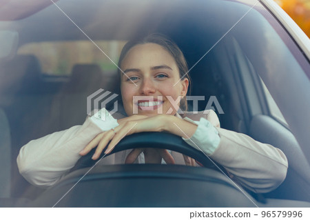 Excited young woman sitting in her car, prepared for driving. Excited young woman sitting in her car, prepared for driving. 96579996