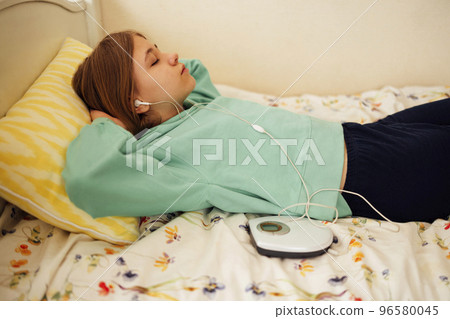 Teenage girl displaying CD and listening to music iin her room 96580045
