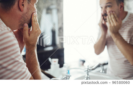 Millennial handsome man looking in mirror, applying moisturizing washing cream 96580060