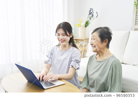 Grandmother using a computer at home with her grandson Grandmother using a computer at home with her grandson 96580353