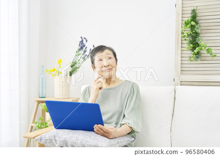 Elderly woman thinking while using a computer at home Elderly woman thinking while using a computer at home 96580406