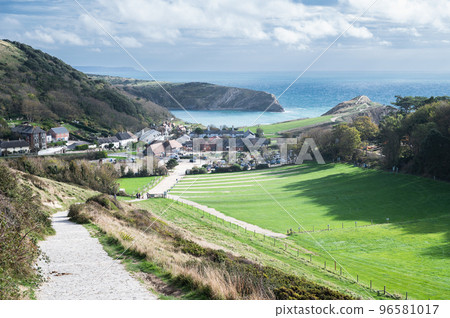 Stone road from Durdle door to Lulworth cove, part of Jurassic Coast World Heritage Site, view of the seaside cottages and Lulworth Cove in the background, selective focus Stone road from Durdle door to Lulworth cove, part of Jurassic Coast World Heritage Site, view of the seaside cottages and Lulworth Cove in the background, selective focus 96581017