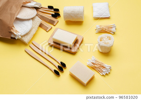 Zero waste with natural self care accessories in paper bag on yellow. Bamboo toothbrushes, handmade soap shampoo bars, cotton buds pads, hygiene products luffa, top view, selective focus Zero waste with natural self care accessories in paper bag on yellow. Bamboo toothbrushes, handmade soap shampoo bars, cotton buds pads, hygiene products luffa, top view, selective focus 96581020