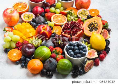 Circle made of healthy raw rainbow fruits, mango papaya strawberries oranges passion fruits berries on oval serving plate on light concrete background, selective focus 96581032