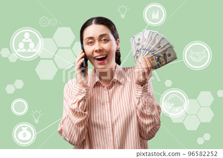 Winning an online lottery. Young happy woman is calling on the phone and holding a fan of dollars in her hand. Turquoise background with digital service.Concept of banking applications and investments Winning an online lottery. Young happy woman is calling on the phone and holding a fan of dollars in her hand. Turquoise background with digital service.Concept of banking applications and investments 96582252