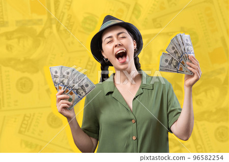 Shopping and investment. Portrait of a happy screaming Caucasian woman wearing straw hat and holding a fan of dollar currency. Yellow background with dollar bills. Win at lottery Shopping and investment. Portrait of a happy screaming Caucasian woman wearing straw hat and holding a fan of dollar currency. Yellow background with dollar bills. Win at lottery 96582254