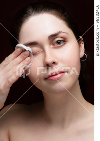 Beautiful girl cleans her face from makeup. Black background 96582416