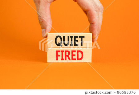 Quiet fired symbol. Concept words Quiet fired on wooden blocks. Beautiful orange table orange background. Businessman hand. Business and quiet fired concept. Copy space. Quiet fired symbol. Concept words Quiet fired on wooden blocks. Beautiful orange table orange background. Businessman hand. Business and quiet fired concept. Copy space. 96583376