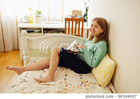 Teenage girl displaying CD and listening to music iin her room 96584087