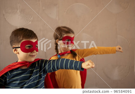 Portrait of a team of two young superheroes, brother and sister, over beige background Portrait of a team of two young superheroes, brother and sister, over beige background 96584091