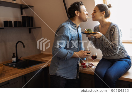 Side view of loving couple eating same spaghetti while having romantic dinner Side view of loving couple eating same spaghetti while having romantic dinner 96584333