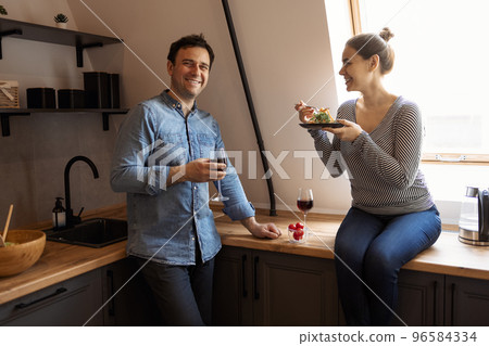Side view of loving couple eating same spaghetti while having romantic dinner together at home 96584334