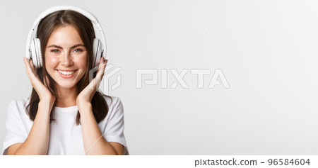 Close-up of beautiful happy girl smiling, enjoying listening music in wireless headphones 96584604