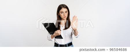 Serious woman with clipboard documents, extending arm, showing taboo stop sign, disapprove, prohibit smth, standing over white background 96584686