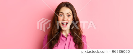 Close up portrait of attractive woman gasping, looking surprised and amazed at camera, hear amazing news, pink background 96586060