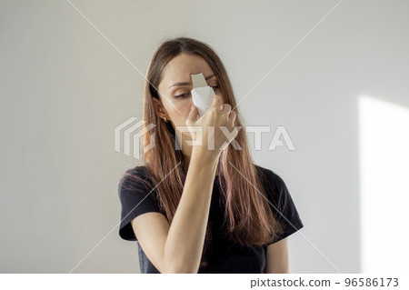 Young woman cleanses her facial pores with an ultrasonic scrubber. Self-care at home. 96586173