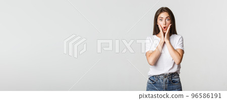 Portrait of surprised and amused brunette girl looking wondered, gasping impressed 96586191