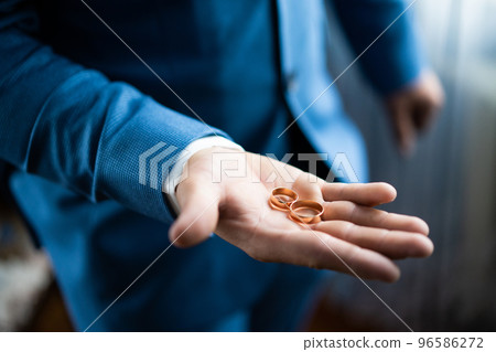 groom holds wedding rings on his palm 96586272