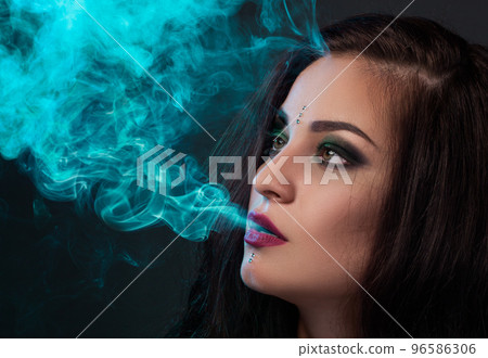 Woman blowing smoke, smoking a cigarette 96586306