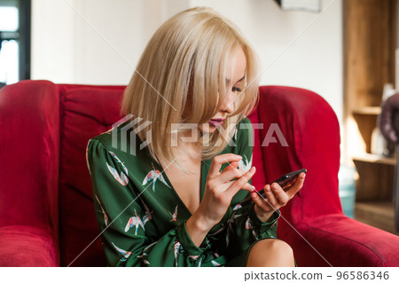 Beautiful woman in green dress typing message on phone 96586346