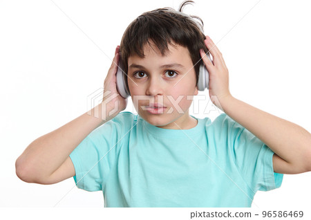 Close-up portrait handsome multi-ethnic teenage boy in turquoise t-shirt, puts on wireless headphones, looking at camera, isolated on white background with copy advertising space for promotional text Close-up portrait handsome multi-ethnic teenage boy in turquoise t-shirt, puts on wireless headphones, looking at camera, isolated on white background with copy advertising space for promotional text 96586469