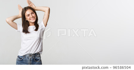Attractive carefree girl showing bunny ears on head and smiling cute 96586504