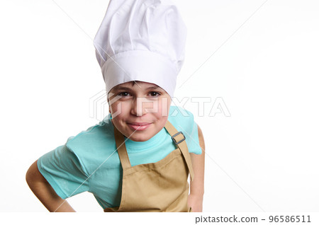 Close-up of an overjoyed happy pre-adolescent child- chef pastry, cook, baker confectioner wearing chef hat and beige apron, isolated on white background. Free ad space. Culinary and bakery concept 96586511