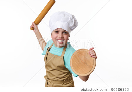 Isolated portrait on white background of a playful teenage boy, baker wearing chef's hat and apron, fighting with a wooden board and rolling pin in his hands, looking at camera. Free advertising space Isolated portrait on white background of a playful teenage boy, baker wearing chef's hat and apron, fighting with a wooden board and rolling pin in his hands, looking at camera. Free advertising space 96586533