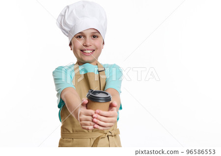 Isolated portrait on white background of a lovely teenage boy, bartender barista, wearing chef's hat and apron, holding selling making a hot tea coffee drink in eco paper cup to go, looking at camera Isolated portrait on white background of a lovely teenage boy, bartender barista, wearing chef's hat and apron, holding selling making a hot tea coffee drink in eco paper cup to go, looking at camera 96586553