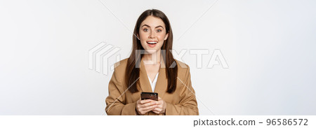 Smiling businesswoman using smartphone, app on mobile phone, standing over white background Smiling businesswoman using smartphone, app on mobile phone, standing over white background 96586572