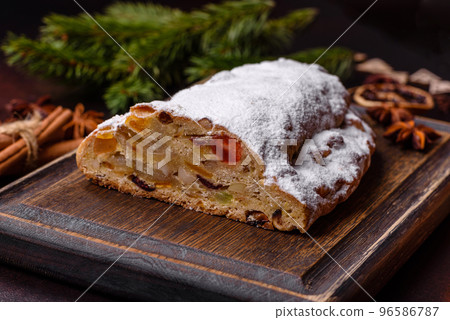 Christmas pie stollen with marzipan, berries and nuts on a dark concrete background 96586787