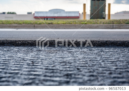low angle selective focus on asphalt overlay paving on top of a concrete base of a residential street 96587013