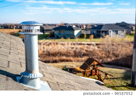 side view of a Galvanized metal chimney exhaust on asphalt roof with a rain cap 96587052