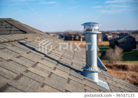 side view of a Galvanized metal chimney exhaust on asphalt roof with a rain cap side view of a Galvanized metal chimney exhaust on asphalt roof with a rain cap 96587135