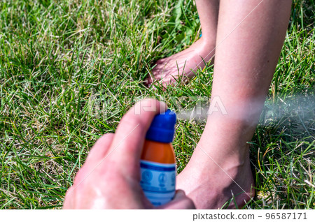 Applying an aerosol spray sunscreen to a young child in the summer.  96587171