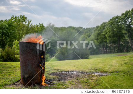 Burn barrel in a rural area used to incinerate trash and garbage. Burn barrel in a rural area used to incinerate trash and garbage. 96587176