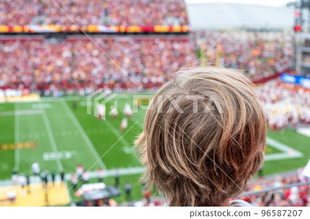 Caucasian boy looking at blurred background of football game Caucasian boy looking at blurred background of football game 96587207