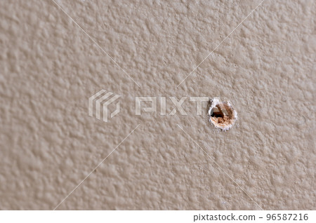 Selective focus on drilled hole through drywall with bits of insulation showing. 96587216