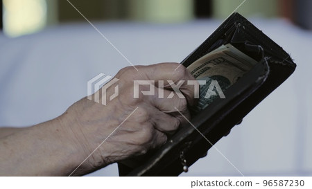 The hands of an elderly woman take out banknotes from an old shabby purse. The poor pensioner counts the last money. Lack of money for life The hands of an elderly woman take out banknotes from an old shabby purse. The poor pensioner counts the last money. Lack of money for life 96587230