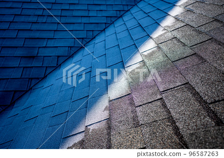 Contrast of frost line on a shingle roof as the sun rises and melts it 96587263