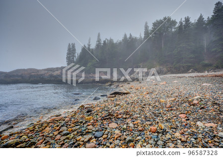 Multi-colored round rocks on Little Hunters Beach in Acadia National Park, Maine. Tide coming in as waves crash.  96587328
