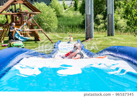 Selective focus on child going down a water slide with water spraying. 96587345