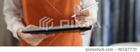 Dry cleaning company worker in uniform, girl hold tablet device with pen, high quality service 96587770