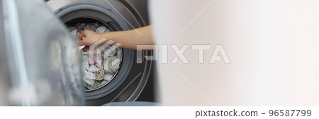 Woman loading washing machine with dirty clothes, taking out clean stuff 96587799
