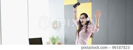 Happy woman dancing on couch, listen to music in headset and sing 96587823